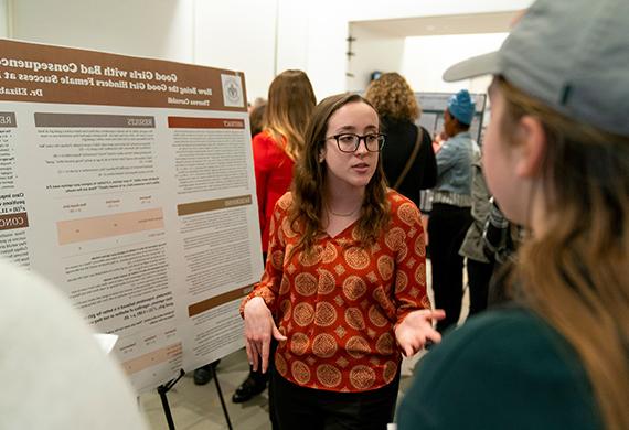 Image of student presenting research to faculty member.